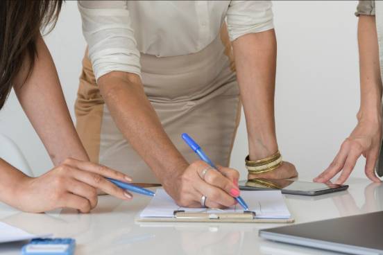 primer plano de las manos de varias personas trabajando en equipo sobre un documento